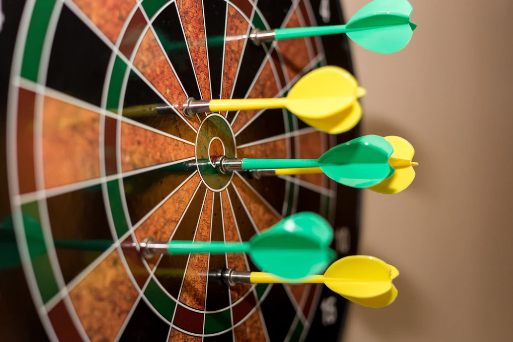 A dart board with darts around the bull's eye to represent accuracy